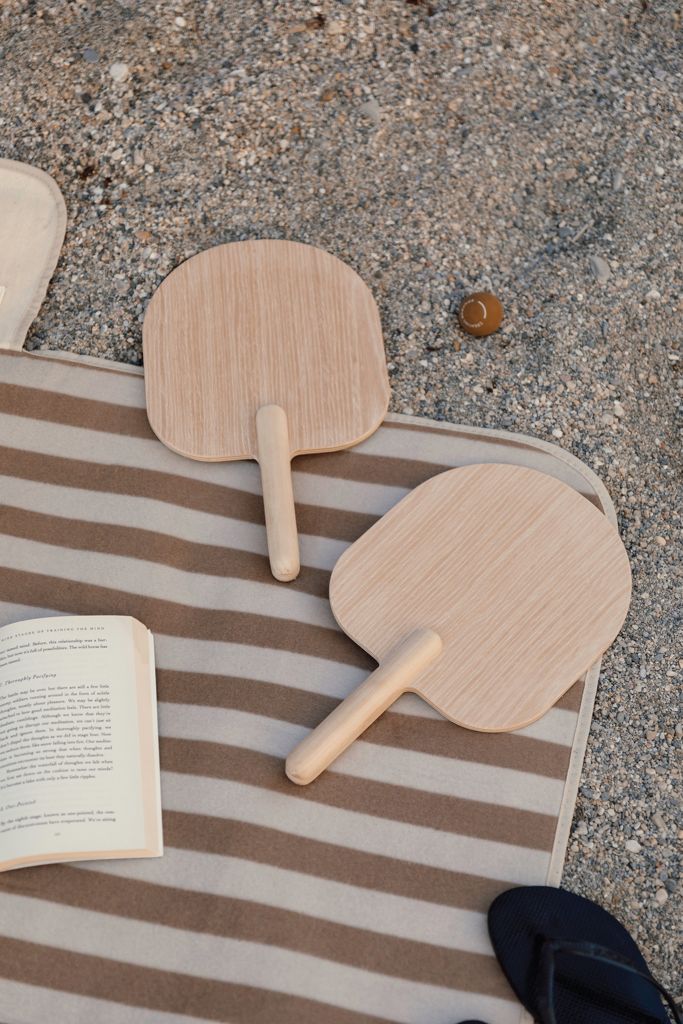 Beach-Tennis-Schläger auf einer gestreiften Decke im Sand