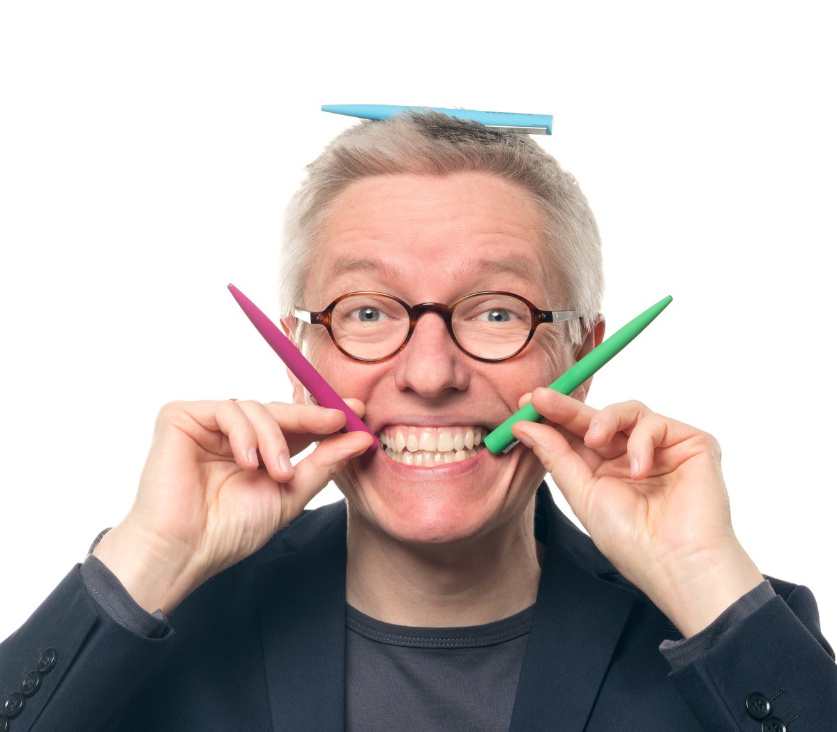 Dr. Bartholomäus Winkler formt mit bunten Werbe-Kugelschreibern ein Lächeln
